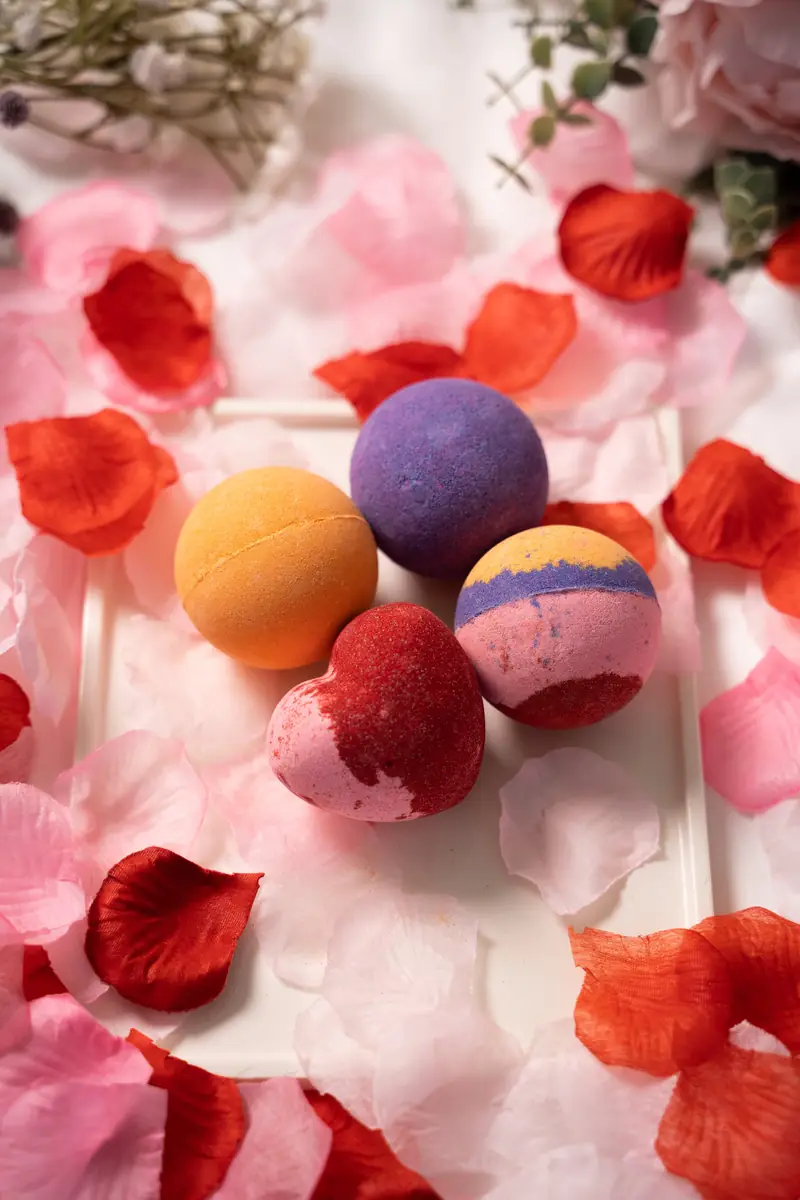 Colourful bath bombs among rose petals