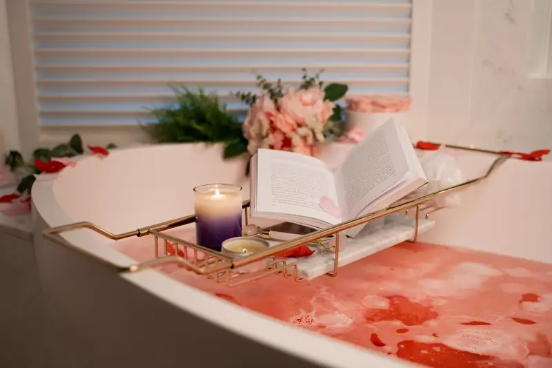 Bath tray with candles and flowers across a bathtub