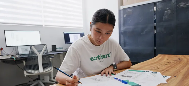 Designer in an Earthero T-shirt sketching cabinet ideas at a desk