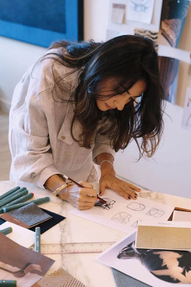 Deborah Guttieres sketching at a table covered in samples