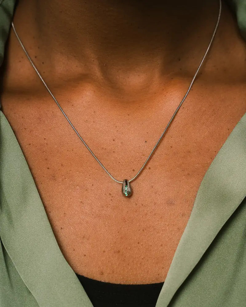 Pendant necklace against a green top