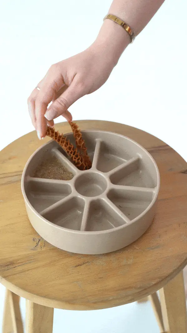 Hand placing treats in a slow-feeder bowl on a stool