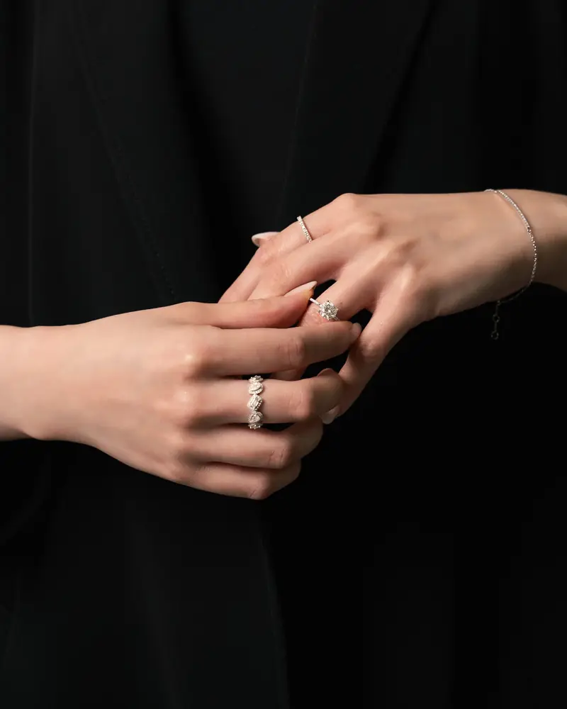 Hands wearing rings against black clothing
