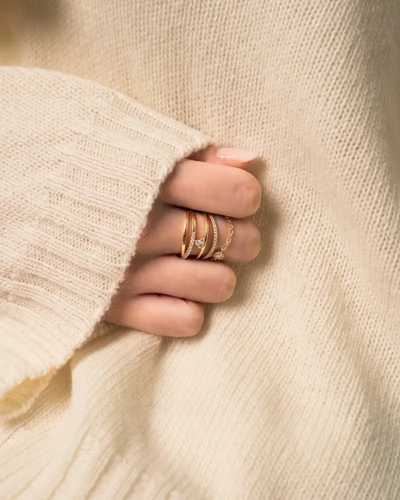 Hand wearing a ring, resting on a cream knit