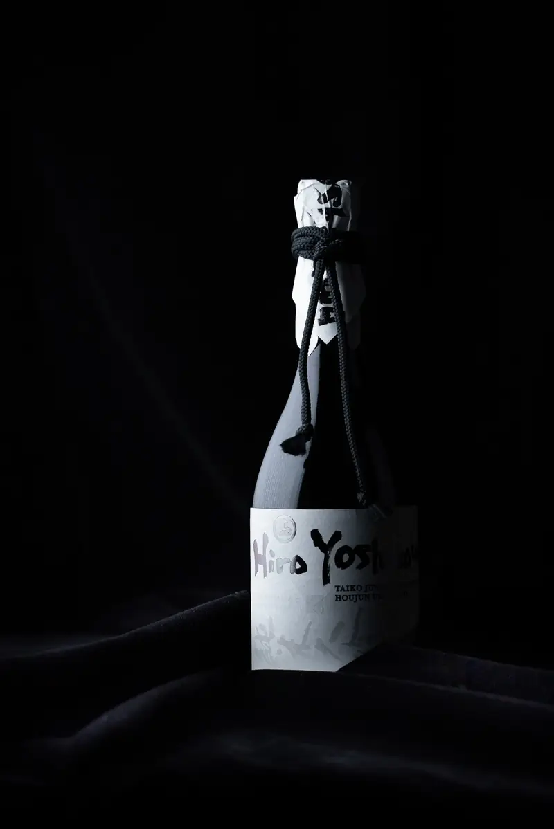 Single sake bottle lit against black