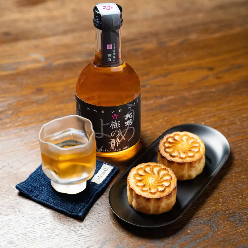 Sake bottle and glass with mooncakes on a wooden tray