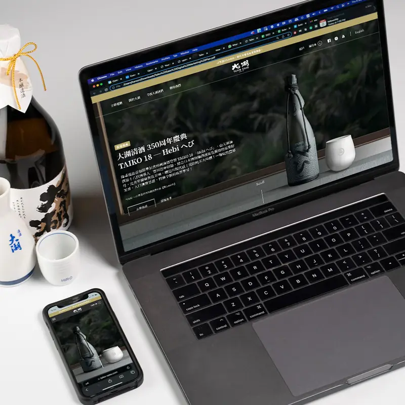Sake bottles beside a laptop showing an online shop