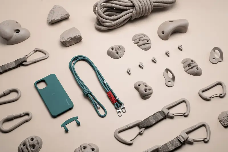 Flat lay of climbing holds, carabiners, a phone case and straps