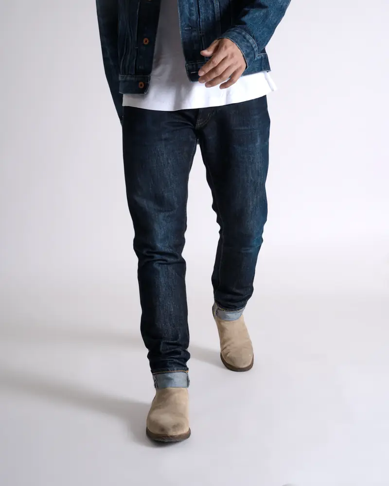 Model in jeans walking against a white backdrop