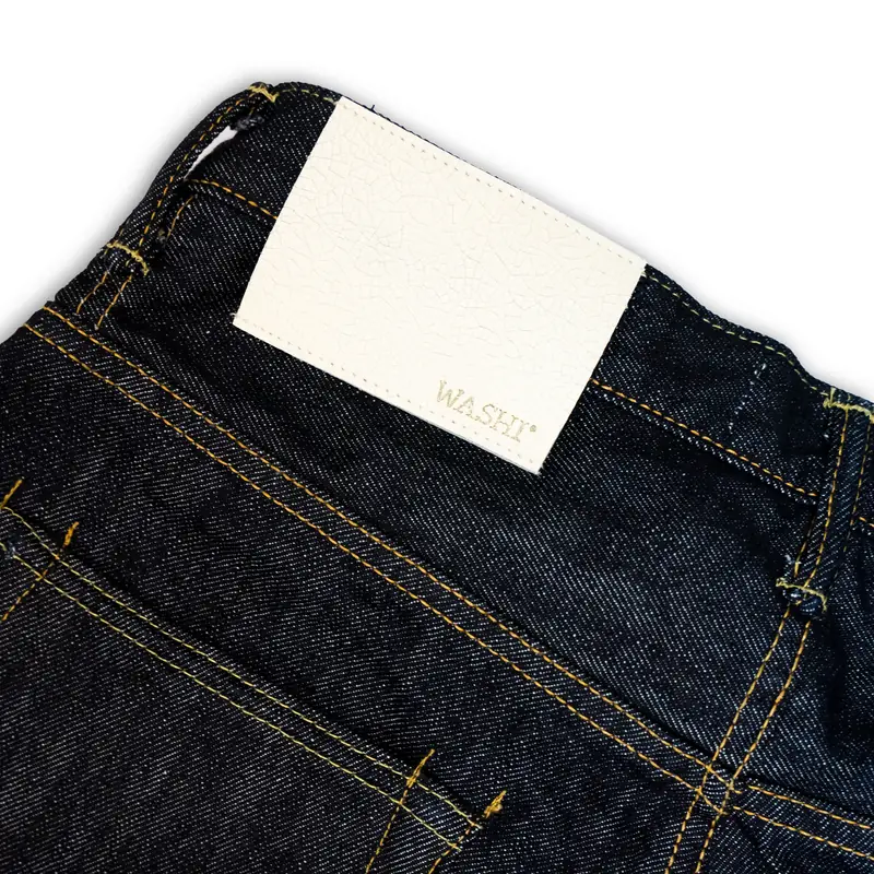 Folded raw denim jeans with a leather patch