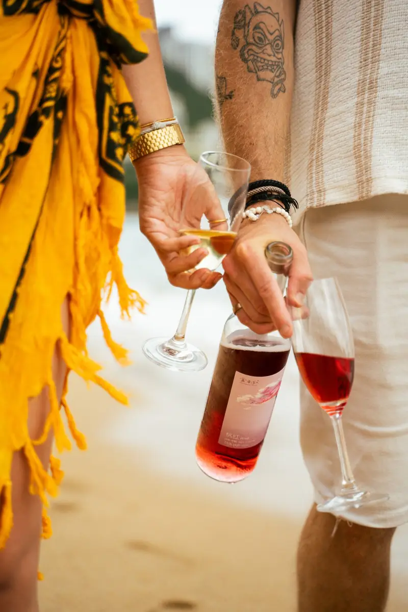 Hands holding wine bottles among tropical leaves