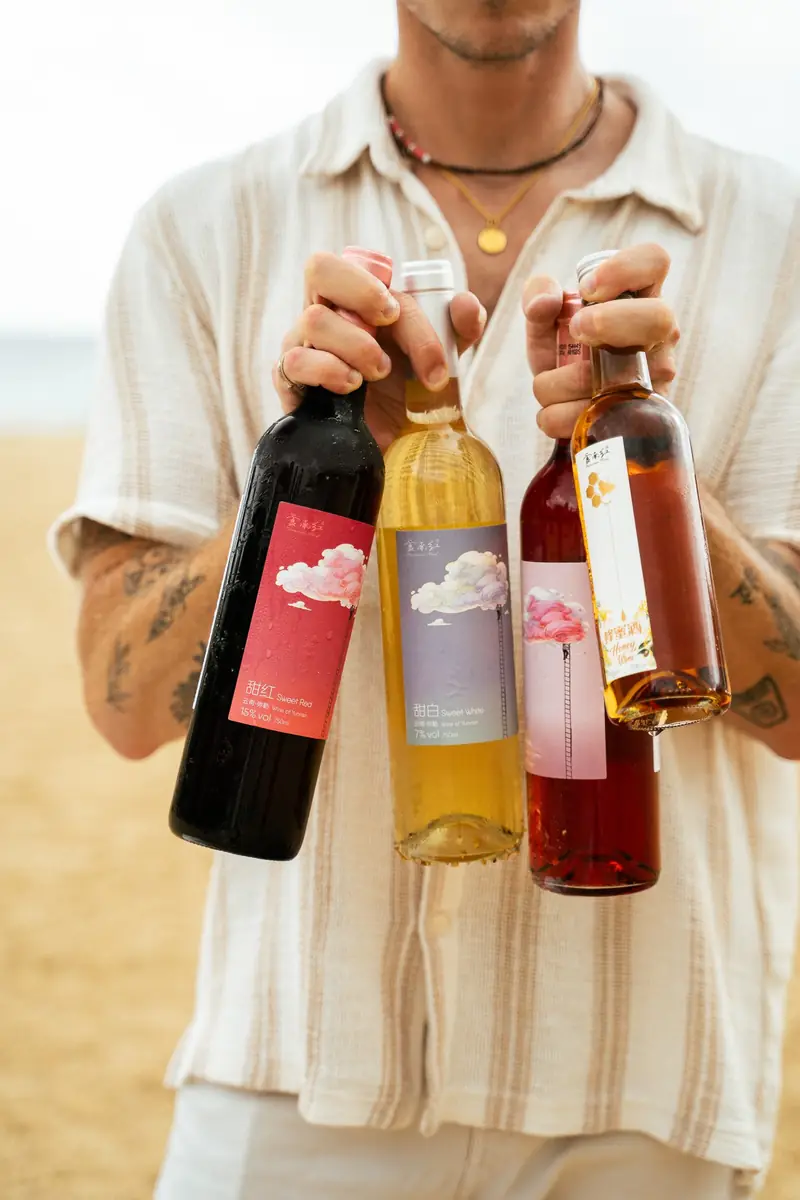 Man holding three bottles of wine on the beach